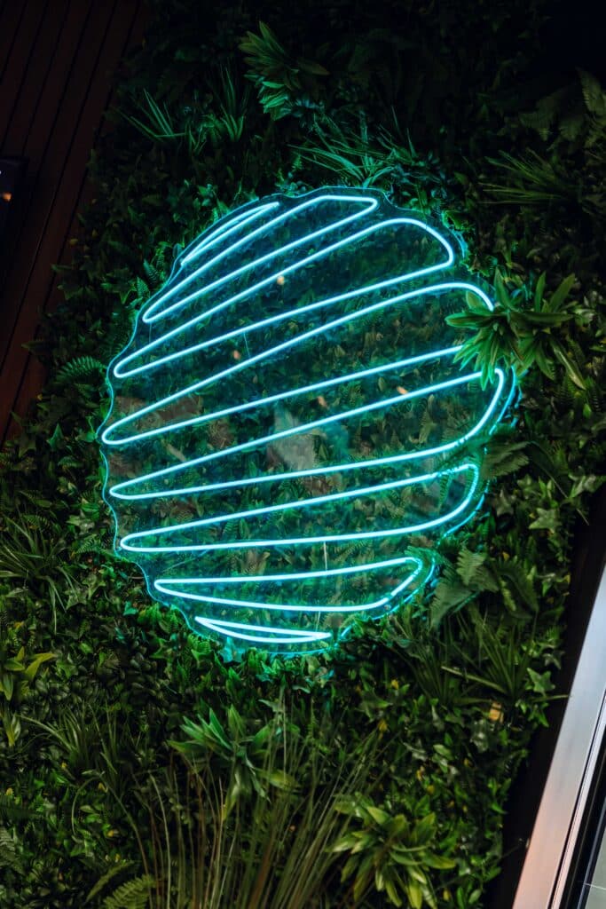 Logo Padel Mate Club in led-verlichting aan een groene muur